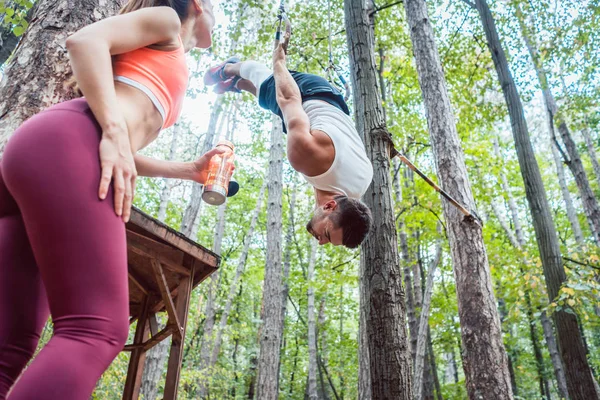 Kvinna och man gör atletisk träning i skogen på ringar — Stockfoto