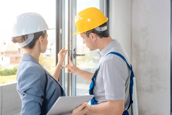 Arquitecto y trabajador de la construcción revisando ventanas en el sitio —  Fotos de Stock