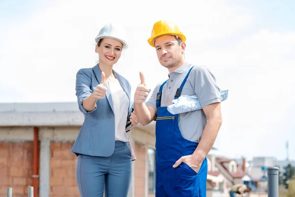 Architect and Construction worker on site giving thumbs-up