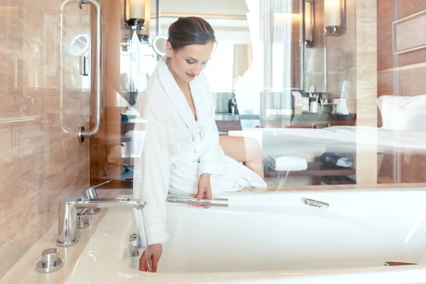 Donna nel lussuoso bagno dell'hotel lasciando acqua nella vasca da bagno — Foto Stock