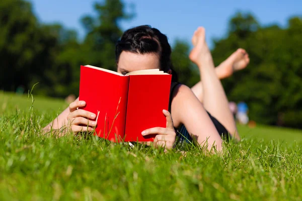 Жінка лежить на траві читає книгу — стокове фото