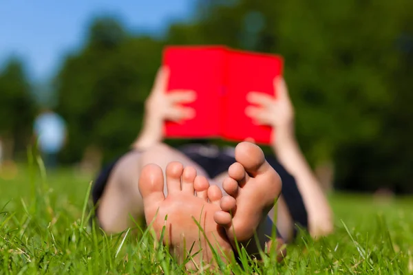 Wanita kaki tergeletak di buku bacaan rumput — Stok Foto