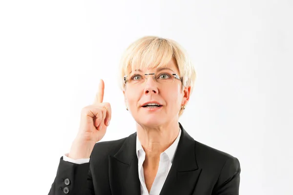 Lächelnde reife Geschäftsfrau zeigt mit dem Finger nach oben — Stockfoto