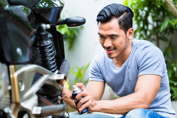 Człowiek, natryskiwania smaru na motocykl — Zdjęcie stockowe