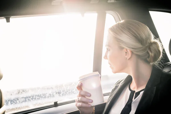 Geschäftsfrau hält Kaffeetasse zum Mitnehmen im Auto — Stockfoto