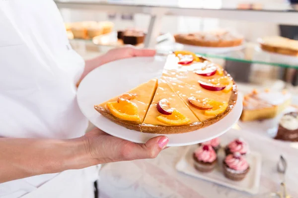 Baker verkoop vrouw zetten van taarten en gebak op display — Stockfoto