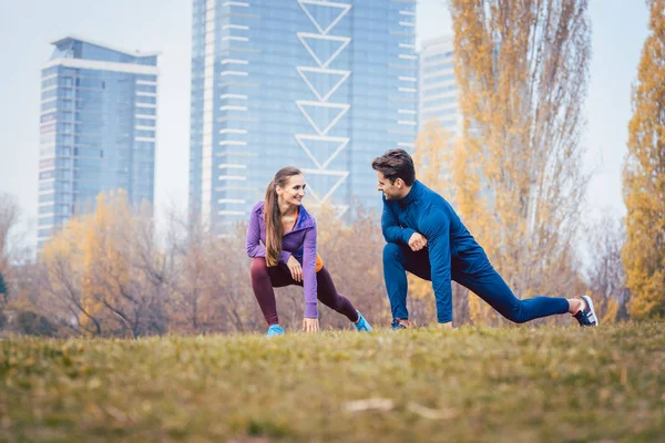 Esporte casal fazendo exercício de aquecimento antes de iniciar uma corrida — Fotografia de Stock