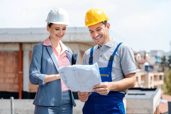 Propietario y trabajador en el sitio de construcción leyendo el plan de planos —  Fotos de Stock