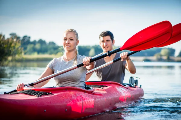 保持幸せな若いカップルは 一緒に湖でカヤック パドルします — ストック写真