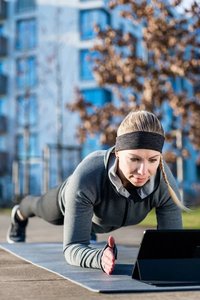 Ung kvinna tittar på en motiverande video när du tränar utomhus — Stockfoto