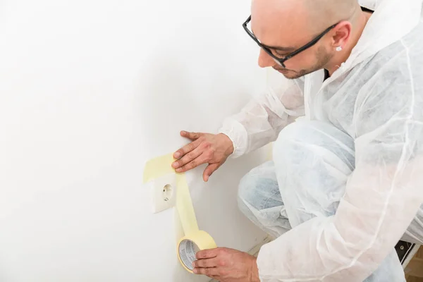 Painter sticking the tape near the plug — Zdjęcie stockowe