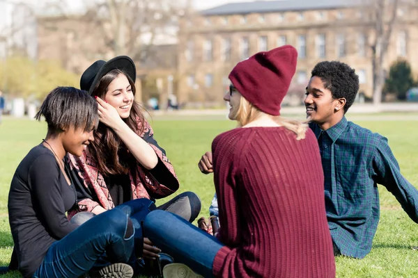 Amigos multiétnicos sentados juntos en el parque — Foto de Stock