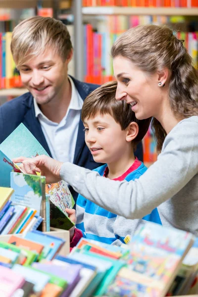 Family reading a book in the library — Stock Photo, Image