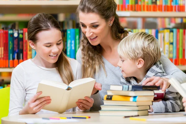 Teacher with her class visiting the library reading books — Stock Photo, Image