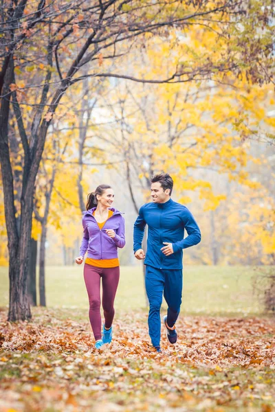 Man and woman running as fitness sport in an autumn park — Stock Photo, Image