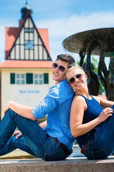 Couple assis dos à dos près de la fontaine — Photo