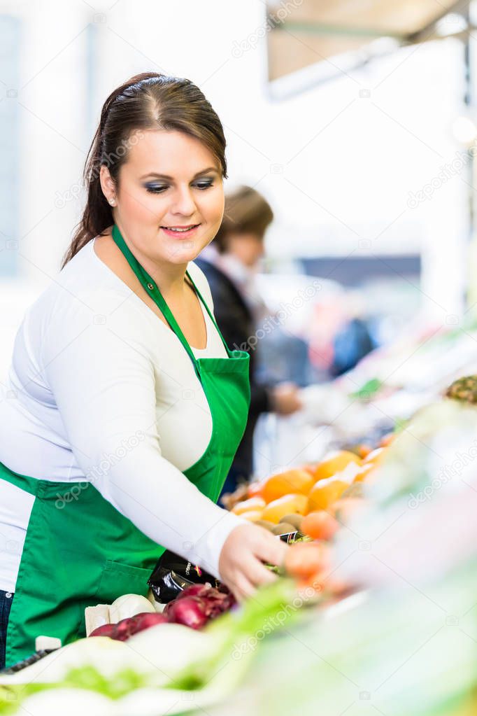 Saleswoman with fruit and vegetables at famers market 