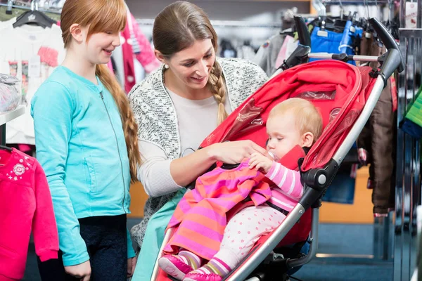 Meisje op zoek bij moeder het verzorgen van baby in winkel — Stockfoto
