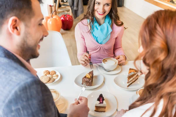 Glückliches Paar sitzt mit ihrem gemeinsamen Freund am Tisch in einem tren — Stockfoto