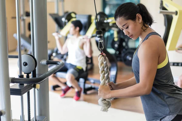 Determined young woman exercising cable rope triceps extension