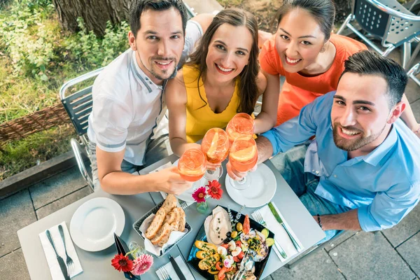 Hoge-hoekmening van vier vrolijke vrienden kijken camera terwijl — Stockfoto