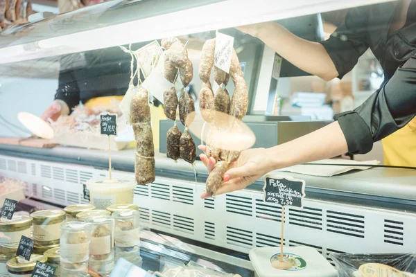 Verkäuferin im Feinkostladen an der Fleischtheke schneidet Würstchen — Stockfoto