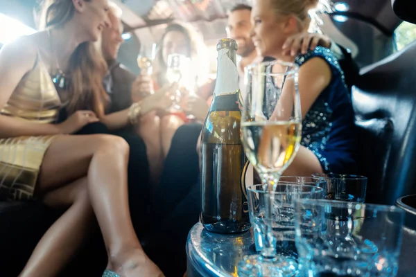 Mujeres y hombres celebrando con bebidas en un coche de limusina — Foto de Stock