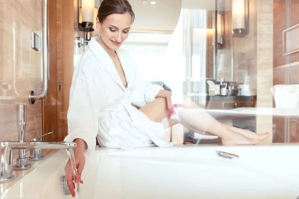 Femme dans la salle de bain luxueuse de l'hôtel laissant l'eau dans la baignoire — Photo