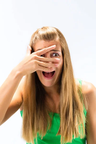 Mujer asustada asomándose de los dedos sobre la cara — Foto de Stock