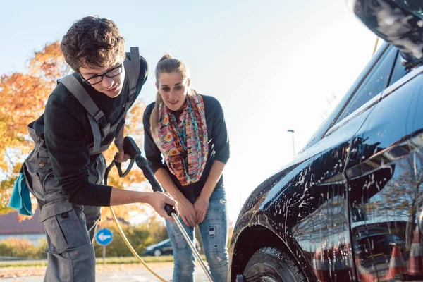 Hombre de servicio ayudando a la mujer a limpiar su auto en lavado de autos — Foto de Stock