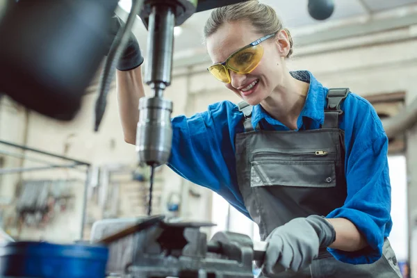 Vrouwelijke werkneemster in metaalwerkplaats met behulp van sokkelboor — Stockfoto