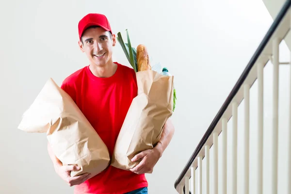 Entrega macho sosteniendo dos bolsas de papel de supermercado —  Fotos de Stock