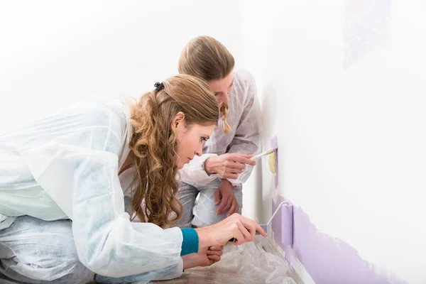Zwei Arbeiterinnen geben lila Farbe an die Wand — Stockfoto