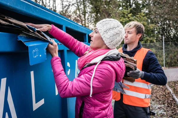Женщина и мужчина помещают макулатуру в контейнер на перерабатывающий центр — стоковое фото