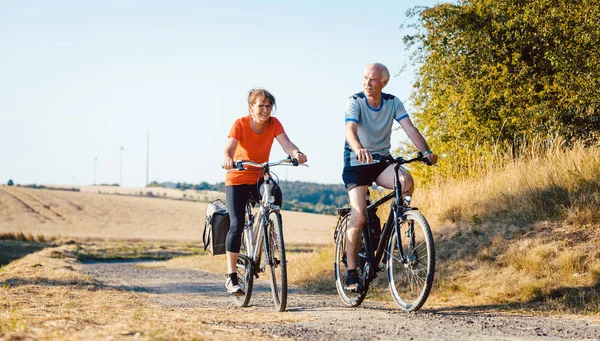 Casal sênior montando suas bicicletas para uma melhor aptidão — Fotografia de Stock