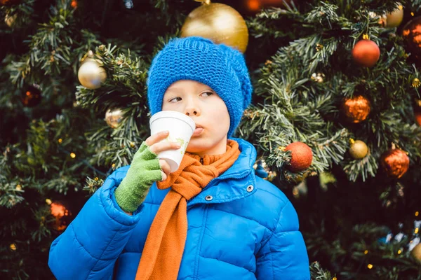 Молодий хлопчик насолоджується випивкою на Різдвяному ринку — стокове фото