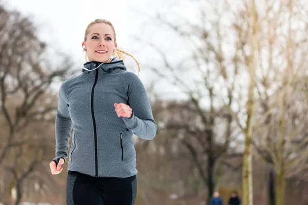 Mujer corriendo por un camino en el día de invierno en el parque — Foto de Stock