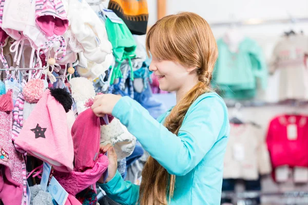 Menina comprando chapéu de lã da loja — Fotografia de Stock