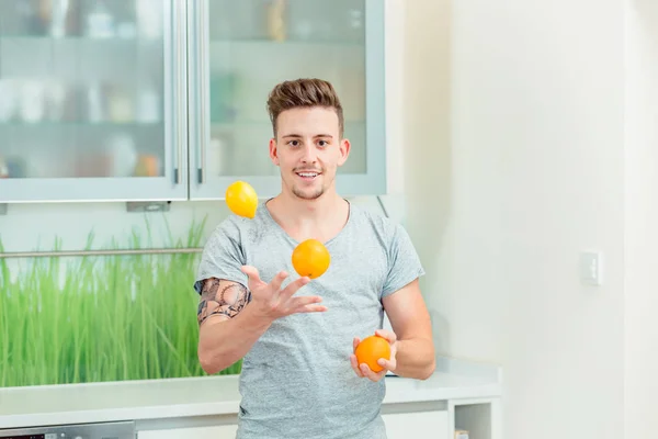 Молодой человек жонглирует свежими апельсинами — стоковое фото