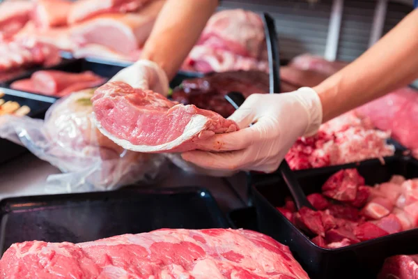 Carne em uma exposição do açougue que está sendo posta dentro pela mulher das vendas — Fotografia de Stock