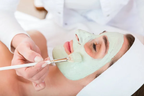 Esteticista aplicando máscara de descascamento facial para a mulher — Fotografia de Stock