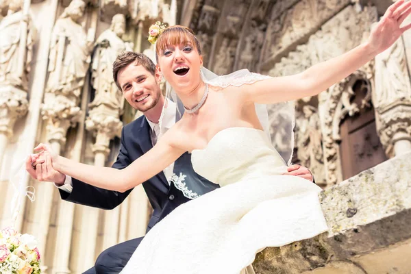 Couple marié excité posant devant l'église — Photo