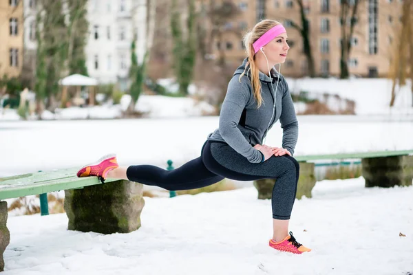 Mujer estirando sus extremidades para hacer ejercicio deportivo en invierno —  Fotos de Stock