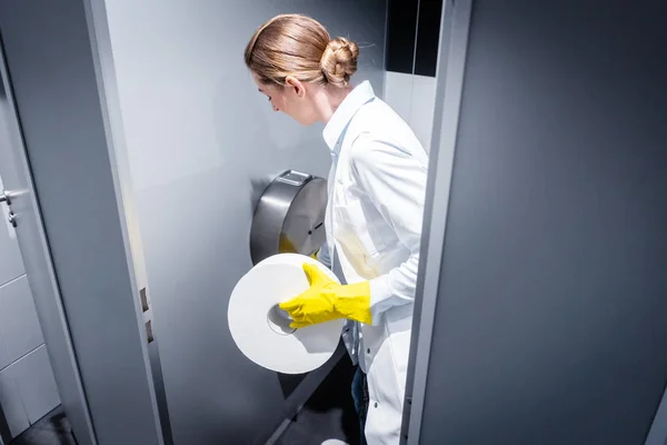 Femme concierge changeant de papier dans les toilettes publiques — Photo