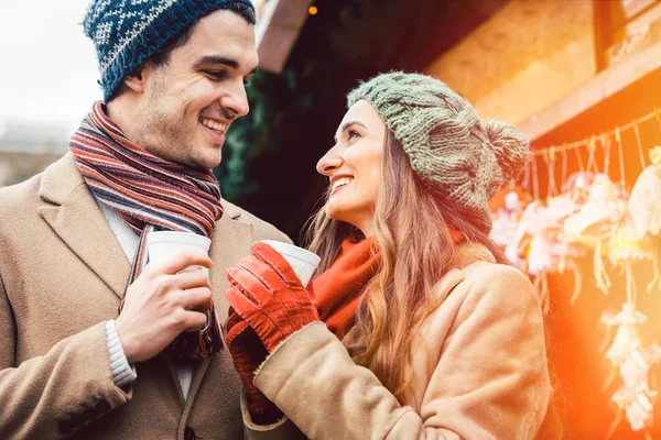 Pareja de pie en el mercado de Navidad frente a un puesto de regalos — Foto de Stock