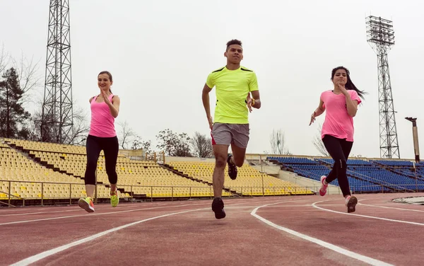 Amici che corrono sul campo sportivo — Foto Stock