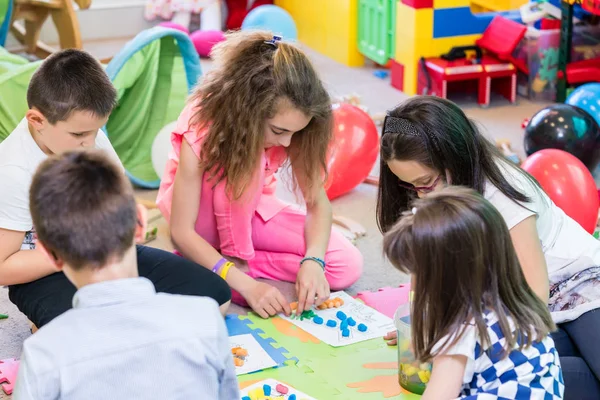 Grupo de crianças que aplicam plasticina colorida durante a atividade educativa — Fotografia de Stock