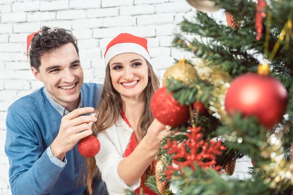 Couple at home decorating tree for Christmas