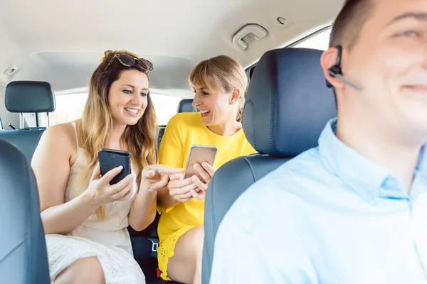 Freundinnen benutzen ihr Handy auf dem Rücksitz des Taxis — Stockfoto