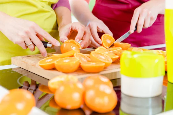 Две женщины режут апельсины — стоковое фото